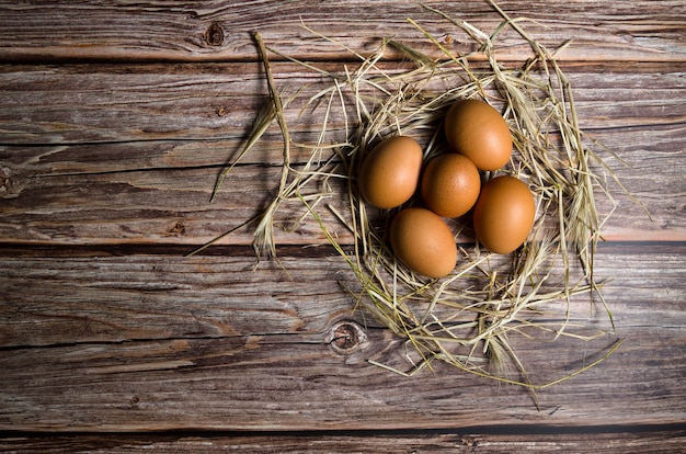 Oeufs bruns avec de la paille sur un fond en bois