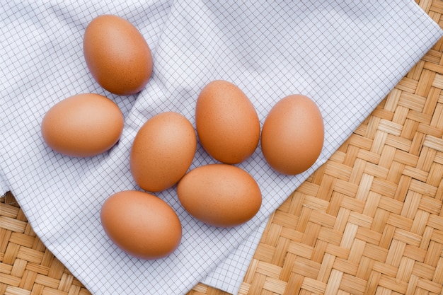 Des œufs bruns pondent sur un tissu à carreaux blanc. Concepts d'aliments sains.