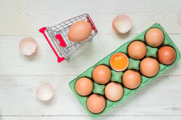 œufs bruts de poulet brun dans une boîte en carton vert et un panier d'achat