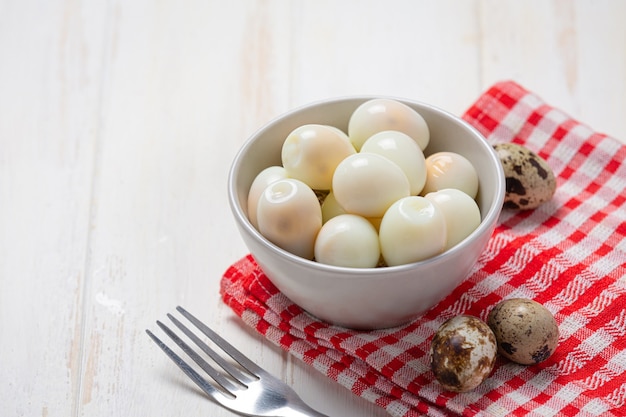 Oeufs de caille bouillis sur la surface en bois blanc.