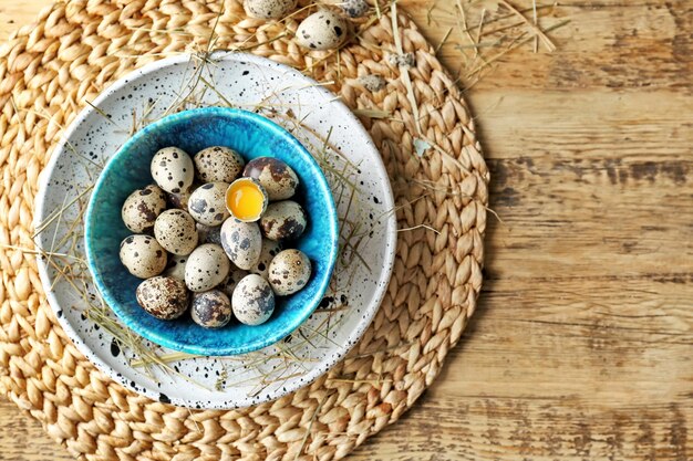 Oeufs de caille crus dans un bol sur une table en bois