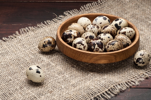 Oeufs de caille dans une assiette en bois sur du vieux bois foncé