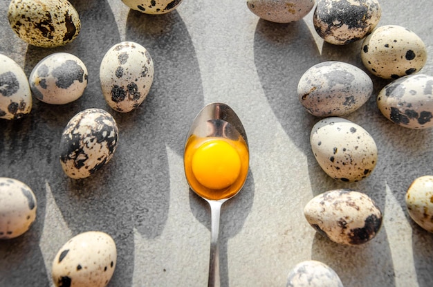 Oeufs de caille sur fond de béton texturé jaune orange vif en vue de dessus de cuillère en métal