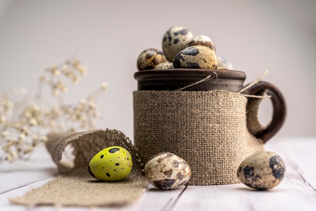 Oeufs de caille frais dans une tasse d'argile sur la table Fond festif de printemps lumineux