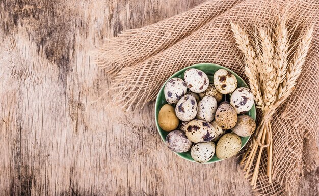 Oeufs de caille frais et épis de blé sur planche de bois