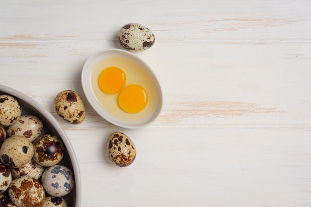 Oeufs de caille frais sur la surface en bois blanche.