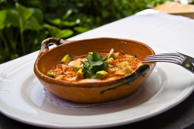 oeufs cassés, plat d'oeufs cassés dans un bouillon de tomate accompagné de couennes de porc et avocat sur une table