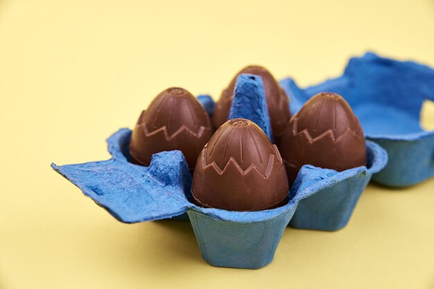 Oeufs en chocolat dans une boîte bleue sur fond jaune avec espace pour faire face Joyeuses Pâques