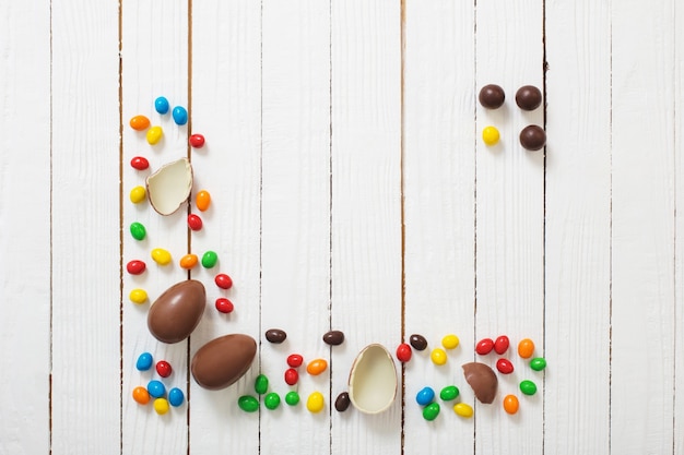 Oeufs en chocolat de Pâques et bonbons sur une surface en bois blanche