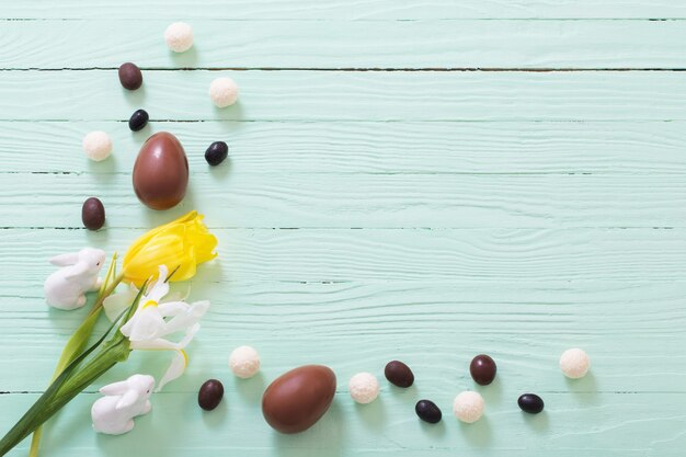 Oeufs en chocolat de Pâques et fleurs sur une surface en bois verte