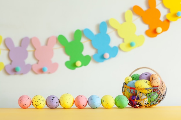 Oeufs colorés dans le panier avec guirlande de Pâques lapin fait à la main sur fond netural. Concept de Pâques.