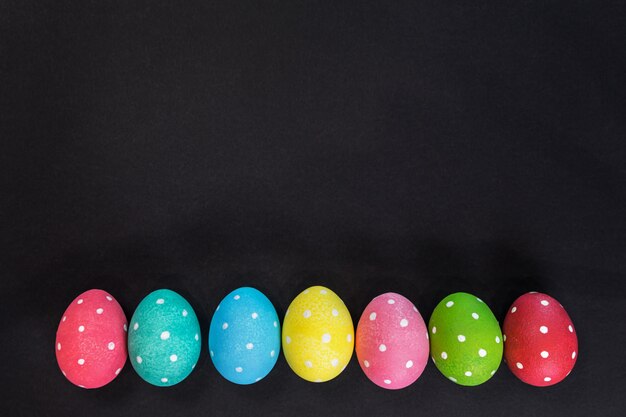 Oeufs colorés décorés pour les vacances de Pâques sur fond noir