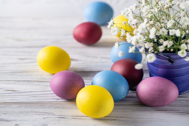 Oeufs colorés joyeuses pâques avec des fleurs blanches de printemps dans un seau