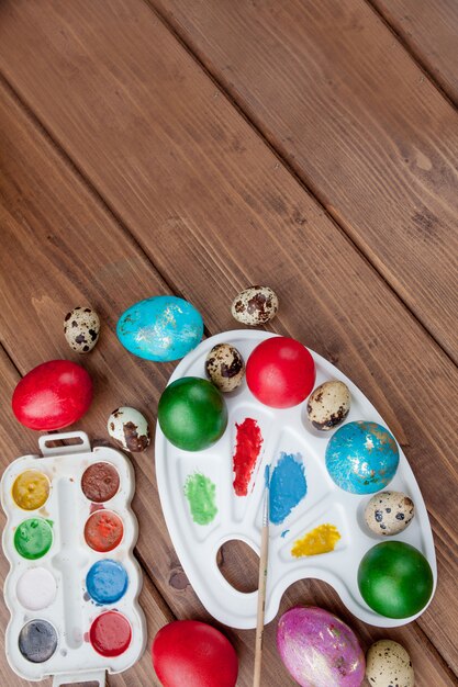 Oeufs colorés et peinture sur une table en bois, fond de Pâques