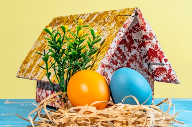 Oeufs colorés symbolisant Pâques avec une maison de jouet fleurit comme un jardin