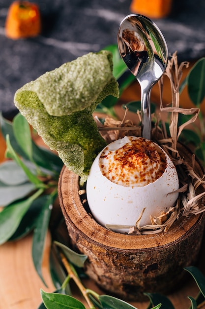 Oeufs à la coque, décorés de petites branches, de feuilles et de paille.