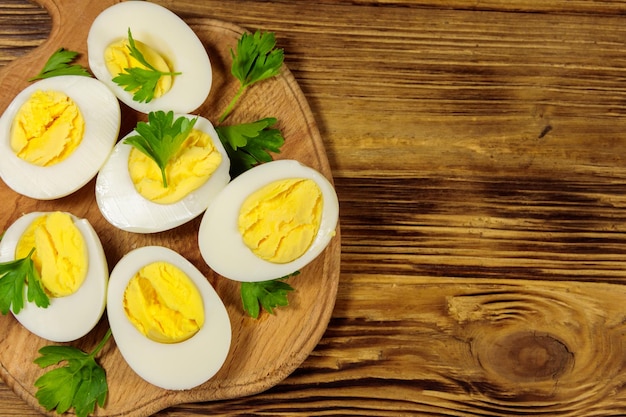 Oeufs à la coque avec du persil sur une planche à découper sur une table en bois Vue de dessus