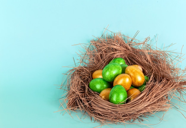 Oeufs de couleur or et vert dans le nid. Le concept de Pâques