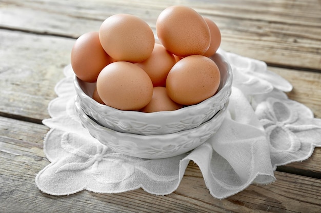 Oeufs crus dans un bol sur fond de bois