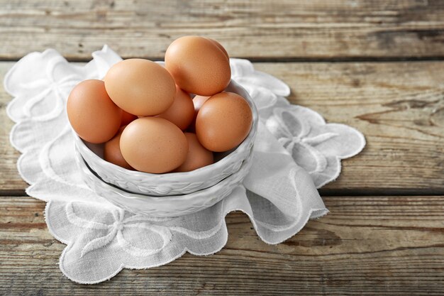 Oeufs crus dans un bol sur une table en bois