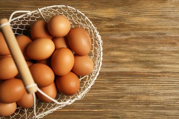 Oeufs crus dans le panier sur fond de bois