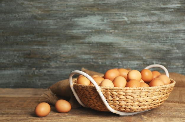 Oeufs crus dans un panier en osier sur table en bois