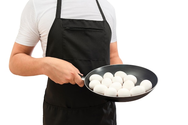 Oeufs crus dans une poêle à frire entre les mains d'un cuisinier isolé sur fond blanc concept de cuisine