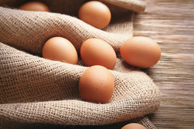 Oeufs crus sur un sac sur une table en bois