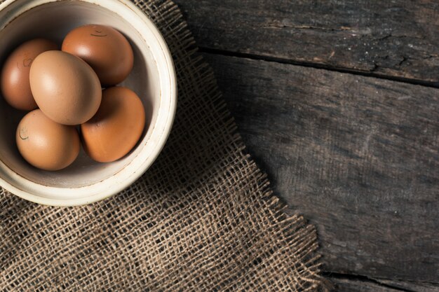 Oeufs dans un bol sur la table des vieilles planches