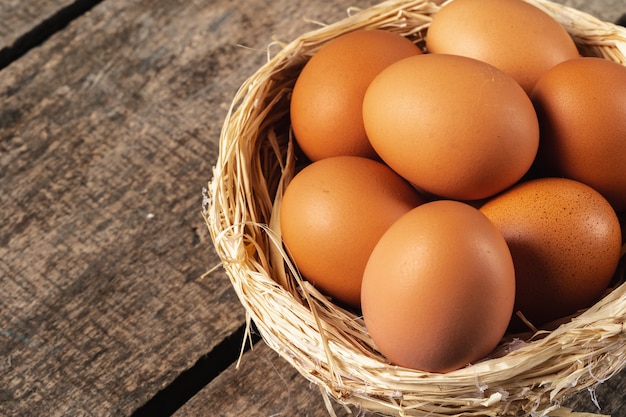 Oeufs dans le nid de foin sur table en bois