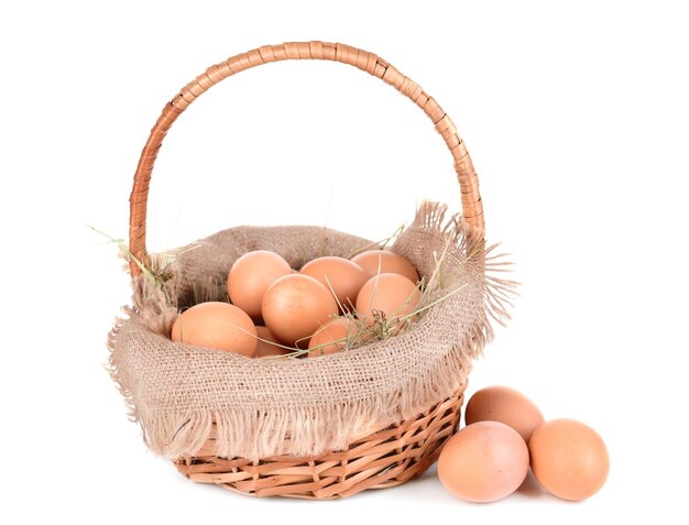 Photo des œufs dans un panier en osier isolés sur blanc