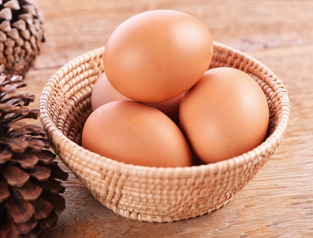 Oeufs dans un panier sur le plancher en bois