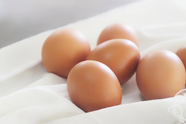 Oeufs dans un sac en tissu blanc sur fond gris.