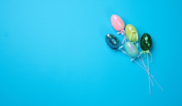 Oeufs décoratifs multicolores de Pâques en paillettes et fond bleu Vue d'en haut