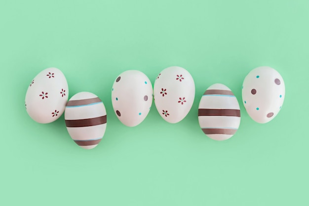 Oeufs décorés de rayures et de fleurs sur fond vert, concept de Pâques.