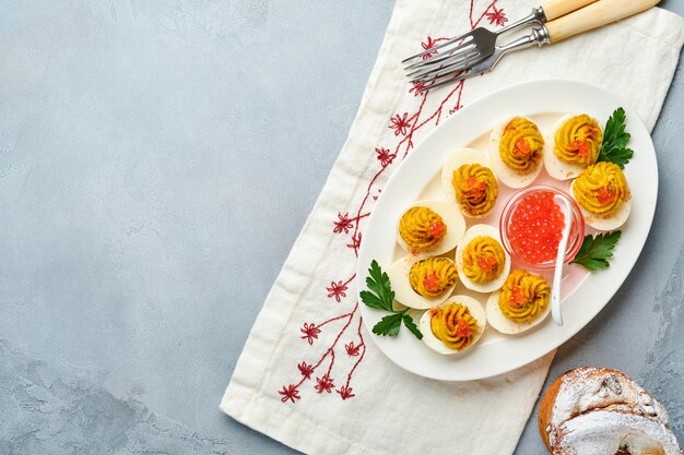 Oeufs farcis au caviar rouge et paprika sur assiette pour apéritif table de pâques