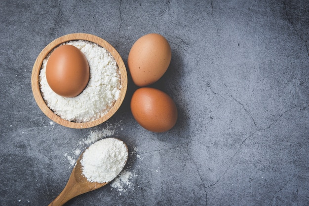 Oeufs de farine maison cuisson des ingrédients sur la table de la cuisine / farine de pâtisserie sur bol en bois sur fond gris