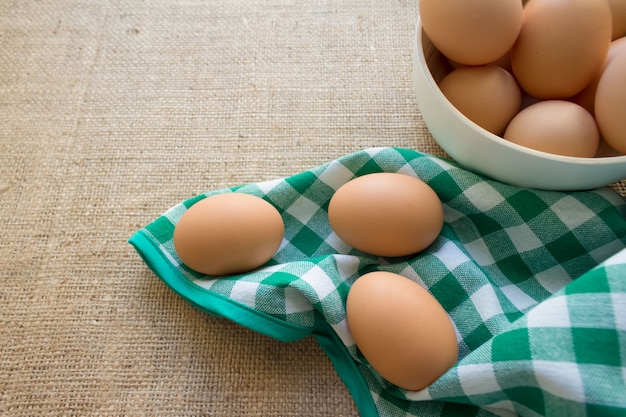 Oeufs frais sur bol blanc et nappe verte