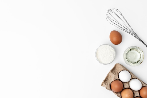 Oeufs frais avec fouet isolé sur fond blanc