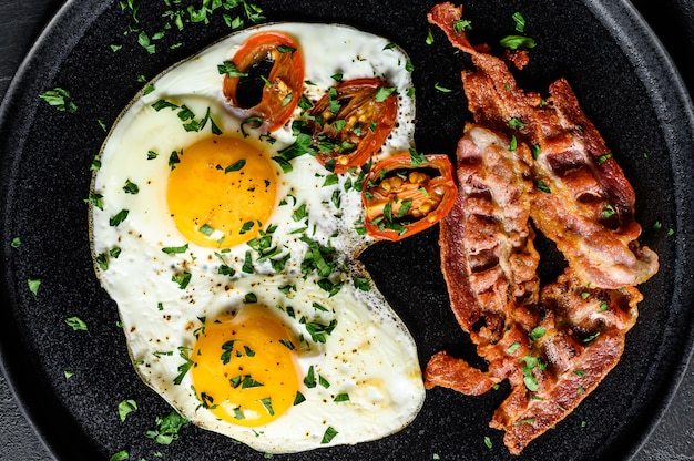 Oeufs frits au bacon. Petit déjeuner classique à l'hôtel. Fond noir. Vue de dessus