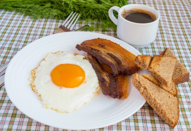 Œufs frits, bacon, pain de seigle, une tasse d'espresso. Petit déjeuner anglais.