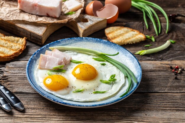 Oeufs frits dans une poêle avec du saindoux de porc, du pain et des oignons verts