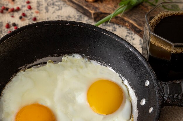 Oeufs frits dans la poêle en fer et tasse de café pour le petit déjeuner