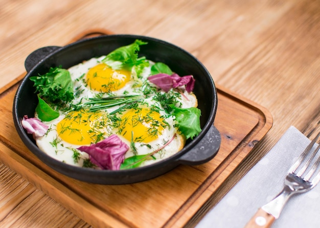 Oeufs frits dans une poêle à frire et verts