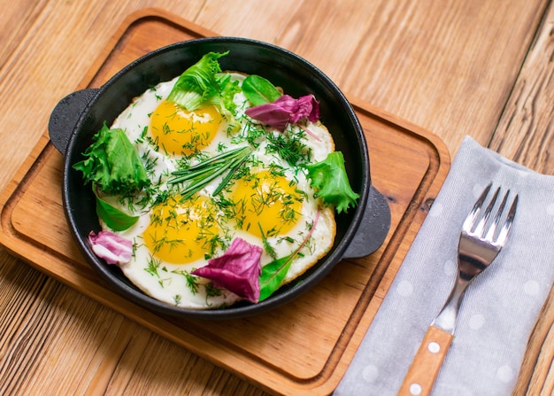 Oeufs frits dans une poêle à frire et verts