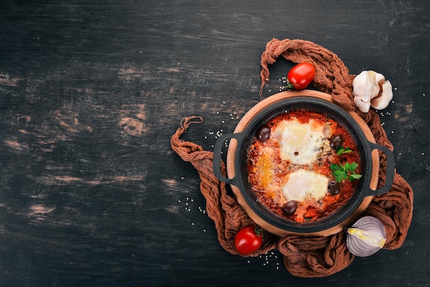 Oeufs frits frits dans une poêle avec des légumes et du parmesan Sur un fond en bois Vue de dessus Espace de copie