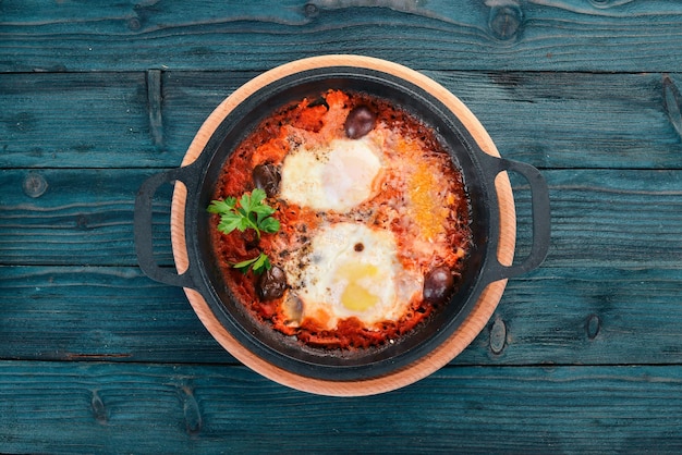 Oeufs frits frits dans une poêle avec des légumes et du parmesan Sur un fond en bois Vue de dessus Espace de copie