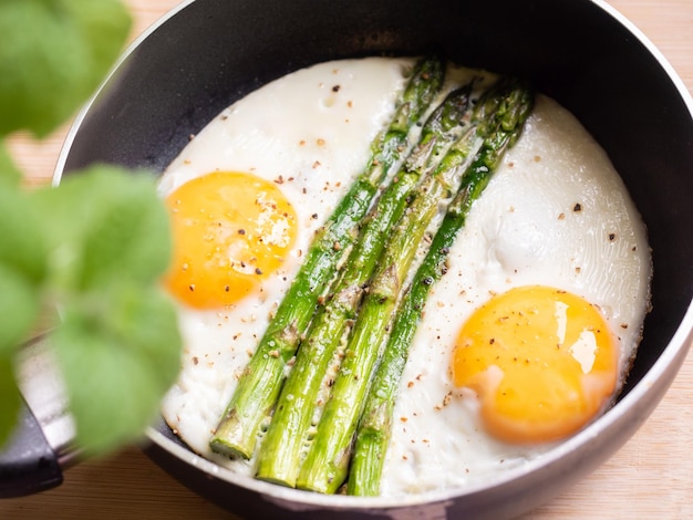 Oeufs frits préparés avec des asperges sur la poêle à frire