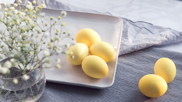 Oeufs jaunes colorés sur Pâques, fleurs de gypsophile décorées sur bannière en tissu gris