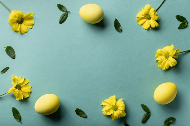 Oeufs jaunes et fleurs sur fond de papier vert. Carte minimale de Pâques. mise à plat, espace copie.